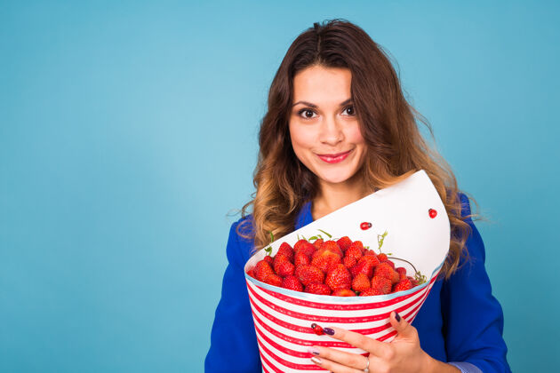 食品拿着一束草莓的年轻女人礼品植物素食