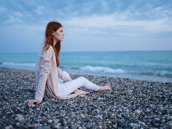 女人一个女人坐在沙滩上的百吉饼上 凝视着大海年轻放松美丽