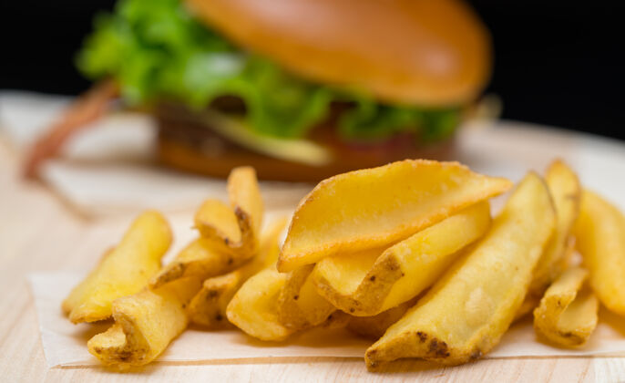 切达酥脆的金色炸薯片或炸薯条与汉堡一起放在木板上 近距离观看蔬菜汉堡包食宿