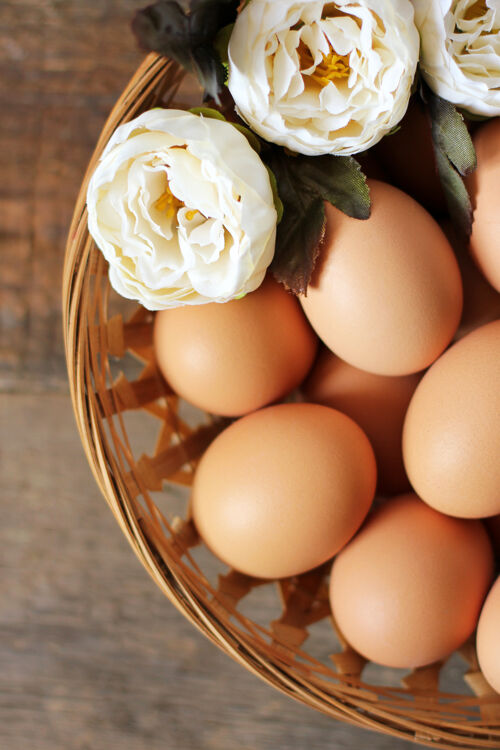 传统鸡蛋和花放在木桌上的篮子里鸡蛋鲜花早餐