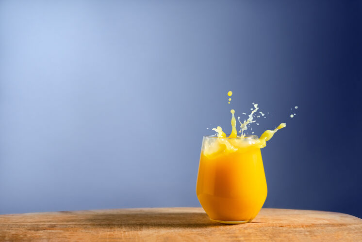 水果一杯新鲜的橙汁溅在木桌上 呈蓝色木材倒刷新