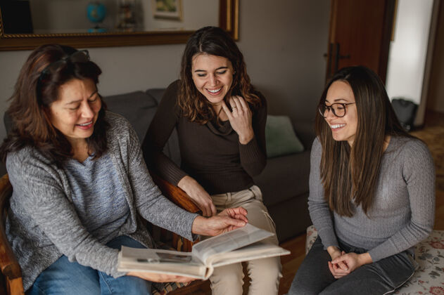 微笑顶视图三个女人 母女俩在看一本书回忆相聚 家庭观念成熟记忆欢呼