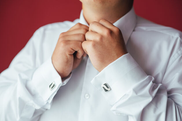 衣柜男手放在一件白色衬衫的表面 袖子上有袖扣和手表 拍下了特写镜头袖口衣服准备