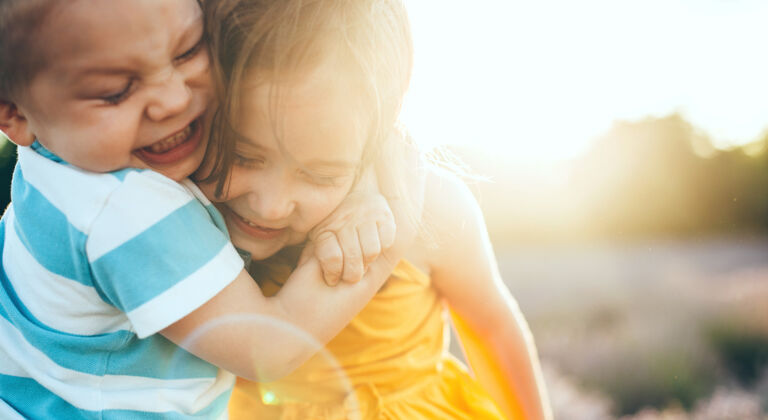 宝贝一个白人小男孩抱着妹妹在外面玩耍的特写照片男孩绿色兄弟
