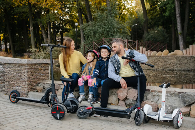 团体一个快乐的大家庭骑着赛格威和电动踏板车在公园里一个温暖的秋日日落女孩城市骑