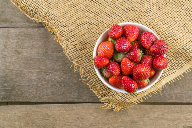 新鲜木桌上碗里草莓的俯视图多汁活力农业