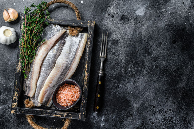 香料腌制海鲱鱼片放在一个木制托盘里 放在黑色的盘子里桌面查看切割晚餐烹饪