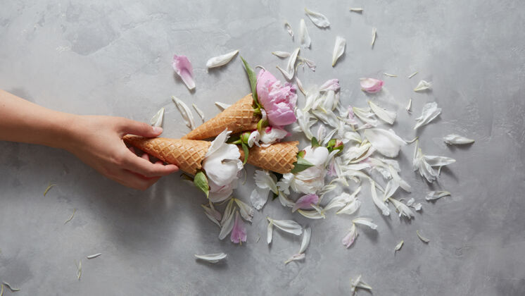 女人甜美的球果在女人的手中与温柔的粉色和白色牡丹花 花瓣上的灰色混凝土背景温柔冰糕自制