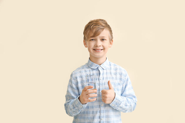 活力可爱的小男孩 拿着一杯水 对颜色竖起大拇指手势寒冷口渴