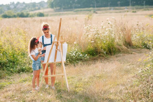 环保家庭 孩子和人的概念-快乐的母亲和女儿在绿色的表面上画画和交谈绘画孩子幼儿园