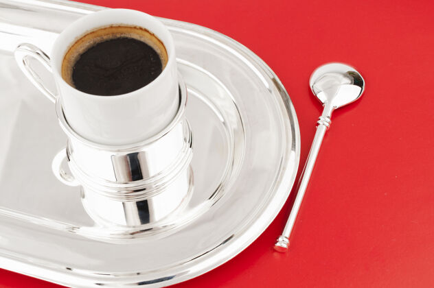 拿铁一杯咖啡放在一个红色背景的金属托盘上银泡沫杯子
