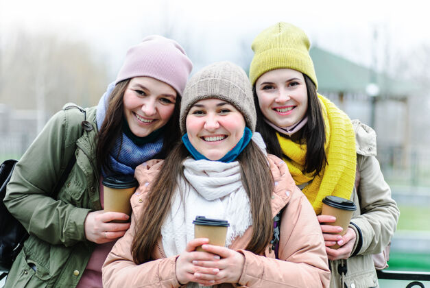 学生戴着低口罩的女孩们看着前面微笑着黑发咖啡友谊