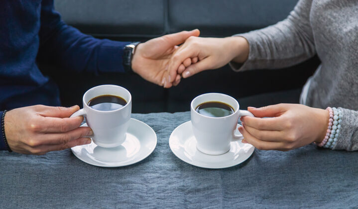 会议一男一女端着一杯咖啡坐在桌边杯子交流朋友