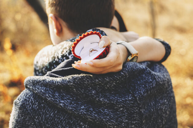 礼物站在秋天的乡间 一个无名女子拿着订婚戒指 拥抱着男友戒指水平无脸