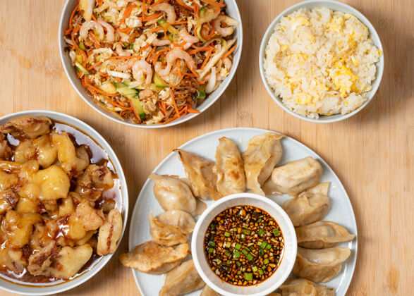 桌子五颜六色的亚洲外卖食品虾沙拉 甜脆鸡 米饭和木制的油炸饺子调色盘肉木头
