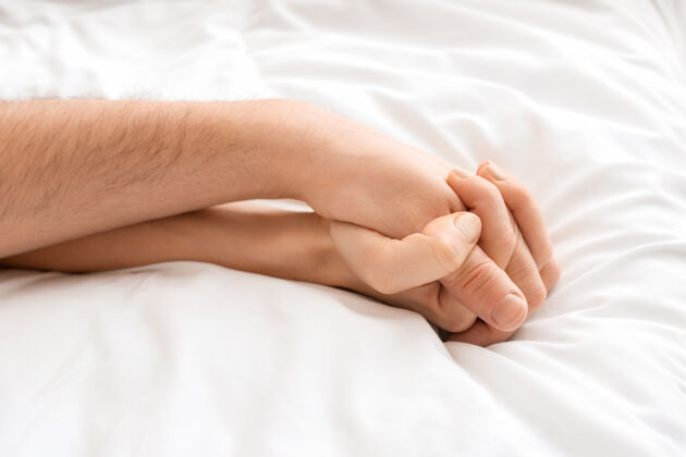 男人睡在床上的年轻夫妇的手男人一起手臂