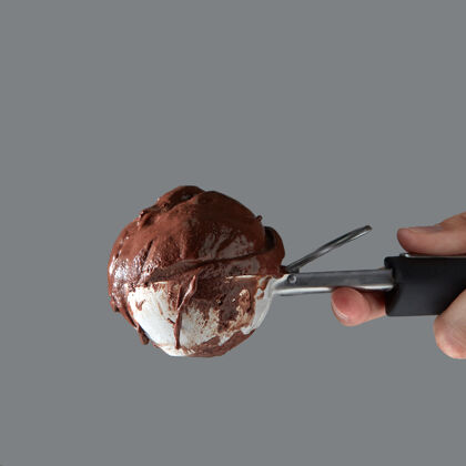 凝胶夏季概念空间文本关闭-在灰色的墙上 一只雌性的手拿着一勺美味的冷巧克力冰淇淋冰勺子美食