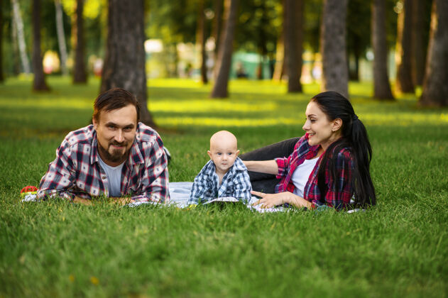 女人妈妈 爸爸和小宝宝在夏日公园的草地上悠闲地玩耍快乐在一起自然