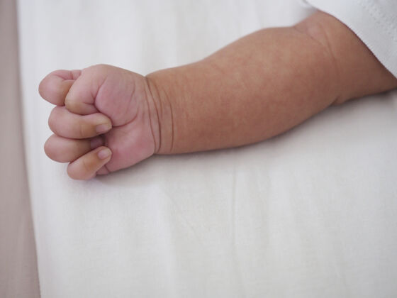 新生儿新生婴儿的手放在白色的床上小童年手臂