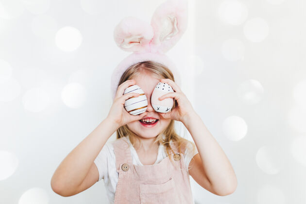 兔子带着复活节彩蛋和兔子耳朵帽子的小女孩童年女传统