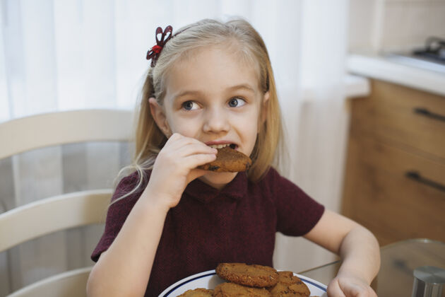 糕点一个可爱的金发小女孩早上在厨房吃饼干的画像饼干微笑享受