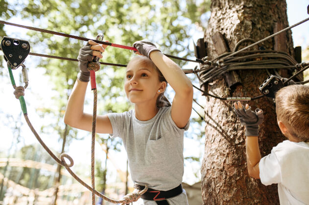 男性小孩子在绳索公园里攀爬网络露营学校