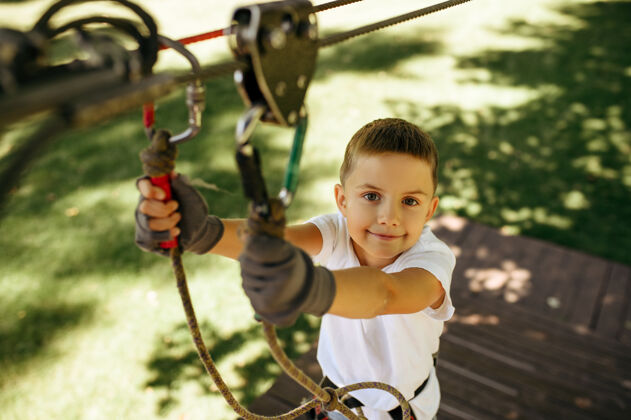 挑战小男孩在绳索公园里攀爬自然攀岩运动