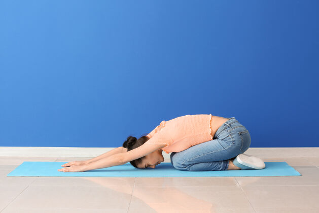 放松在彩墙边练习瑜伽的年轻女子训练休闲灵活