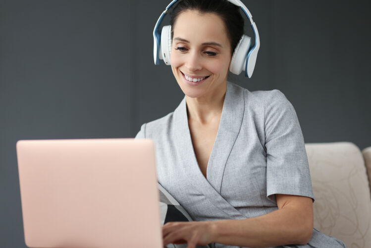 设备戴着耳机微笑的女人在后面工作笔记本电脑.遥控器工作理念通信欢呼外观
