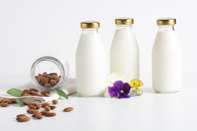 健康食品杏仁牛奶装在玻璃瓶里 站在白色的地板上素食奶天然产品坚果奶
