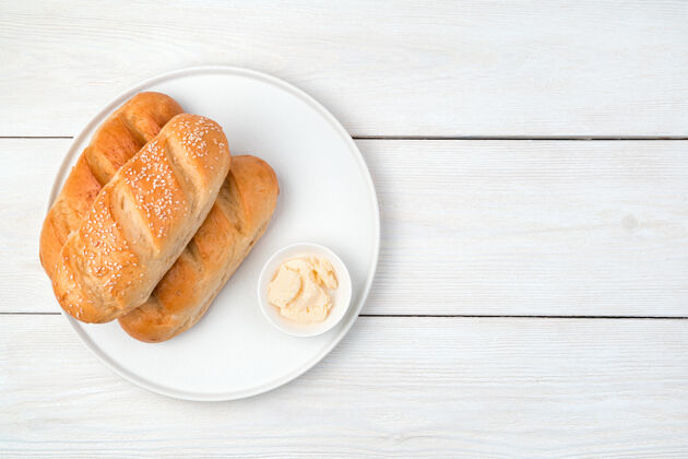 餐桌面包和黄油放在一个白色木制背景的平板上芝麻白色美味