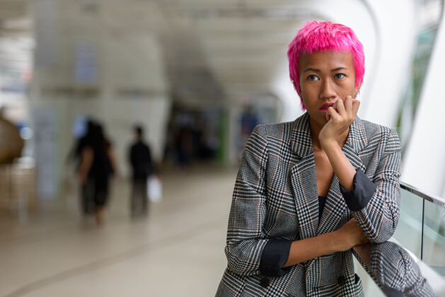 个人年轻叛逆的亚洲女商人的肖像 粉红色的头发在城市户外的人行天桥上时髦客场人行桥