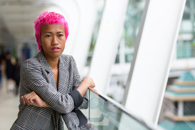 自信年轻叛逆的亚洲女商人的肖像 粉红色的头发在城市户外的人行天桥上现代东南风格