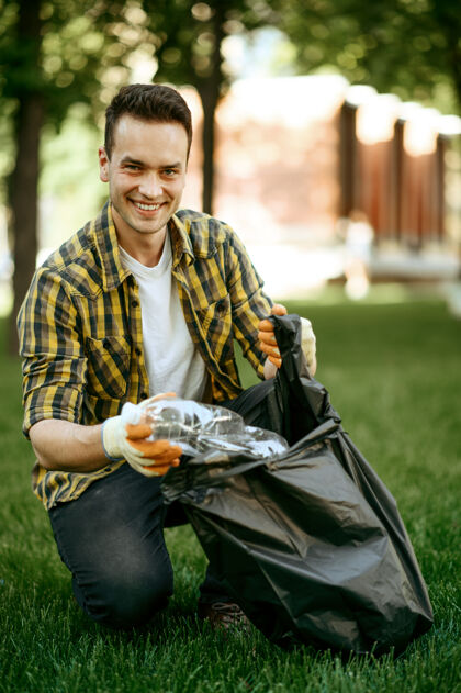 清洁年轻人在公园里用袋子收集垃圾 志愿服务男人清林 生态修复 生态生活方式 垃圾收集回收 生态关爱 环境清洁再利用瓶子垃圾