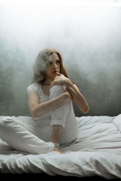医院一个带枕头的疯女人坐在床上 黑乎乎的房间每晚都有问题的人 抑郁和压力 悲伤 精神病院夜晚人肖像