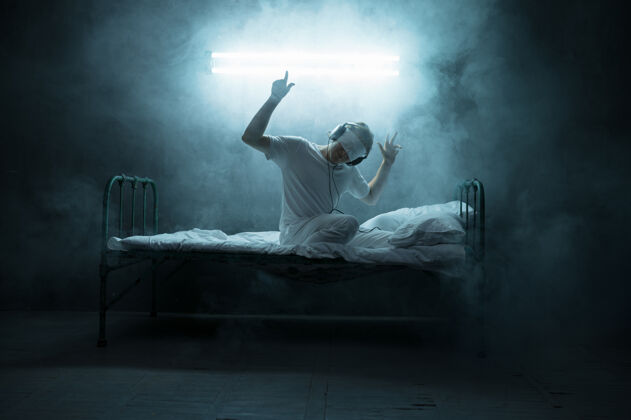 神秘蒙住眼睛坐在床上的精神病男人 失眠恐怖 黑暗的房间…迷幻的男人每晚都有问题 抑郁和压力 悲伤 精神病医院生病悲伤夜