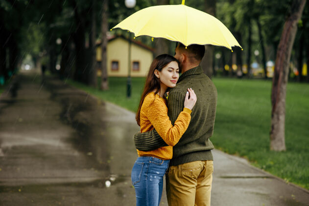 夫妇公园里的情侣拥抱 夏日的雨天戴曼女人站在雨伞下 浪漫的约会在小路上 潮湿的天气在巷子里白天丈夫人