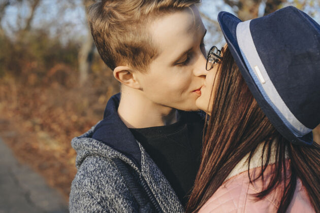 亲吻一对可爱的年轻白种人夫妇在度假旅行约会时在外面亲吻的侧视照片帽子情侣爱