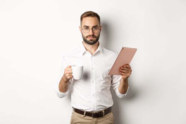 picture自信的男经理 站在白色的背景下 阅读数字平板电脑上的工作 喝咖啡ModelManagerPerson