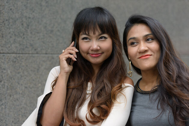 男同性恋两位年轻的亚洲女商人在城市户外的合影公司电话商务女性