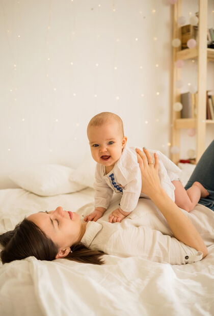 床一位母亲和她的小女儿躺在房间床上的白色毯子上的画像小年轻新生儿