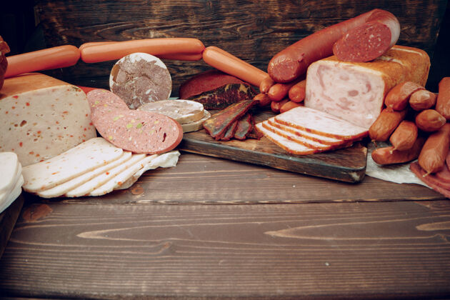 晚餐各种各样的香肠和肉摆在棕色的木制背景上烹饪肉美食