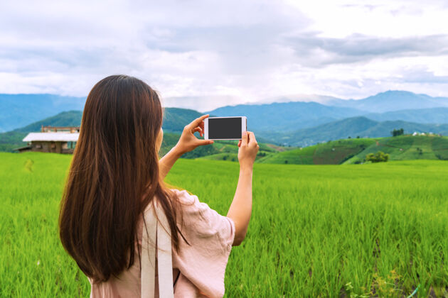 屏幕女游客用智能手机特写在稻田梯田拍照田地农场旅行者