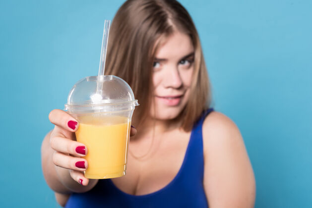 健身尝试它关闭一个胖乎乎的微笑着的女士手里拿着一个盛着橙汁的玻璃杯自然女人大