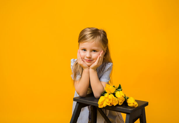 花束一个美丽的金发女孩的肖像 黄色的郁金香在黄色的小女孩黄色郁金香三月