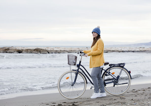 天空春天 戴着帽子的黑发女人骑着自行车在海边散步骑行假期水