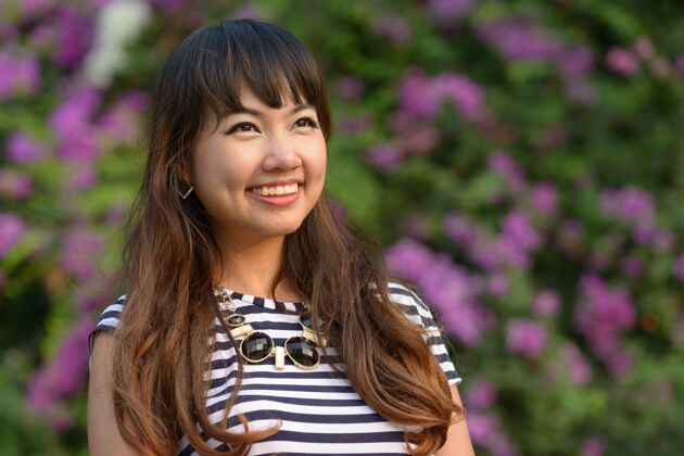 女性年轻美丽的亚洲女子在公园户外放松的写真思想和平发型
