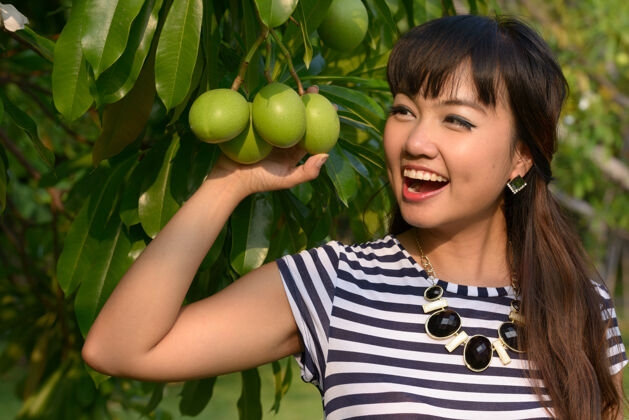 思考年轻美丽的亚洲女子在公园户外放松的写真水果泰国自然