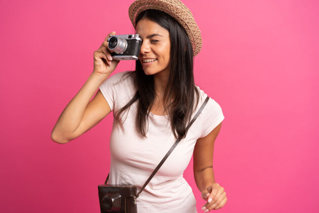 女士一个女人拿着照相机 在粉红色的背景下拍摄照片看欢乐舞蹈