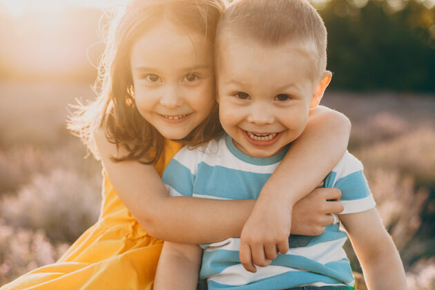 多彩日落时分 一对可爱的小弟弟和妹妹坐在一片花丛里 拥抱着 笑着薰衣草快乐情感